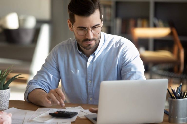 Personne consultant un document sur l'assurance emprunteur avec un ordinateur portable