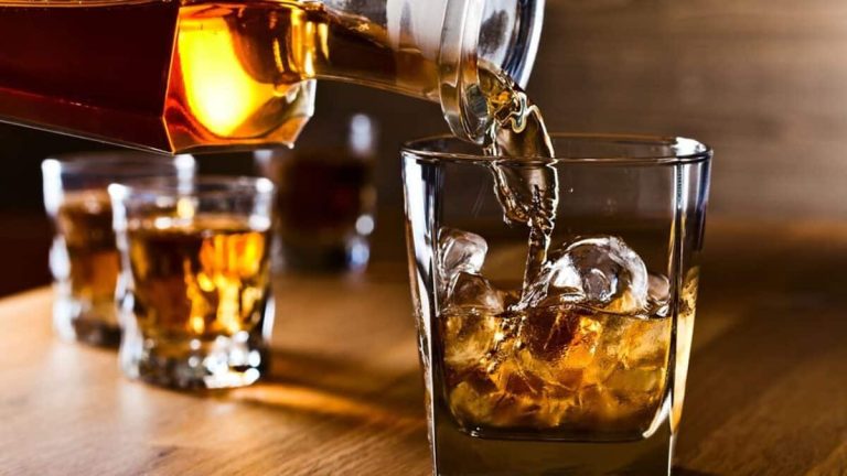 Verre de whisky avec glace sur une table en bois ancien