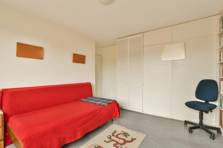 canapé-lit rouge dans une petite pièce avec une chaise