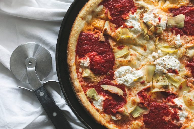Pizza aux artichauts et fromage avec un coupe-pizza