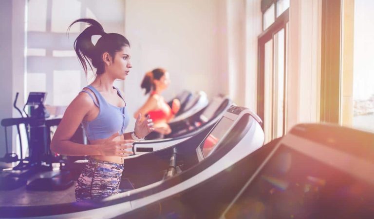 Femme hispanique sportive courant sur un tapis de course en salle de sport