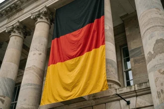 Drapeau allemand noir rouge et jaune accroché sur la façade d'un bâtiment officiel en pierre, vue en contre-plongée