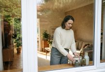 Les fenêtres en PVC et le design d’intérieur : comment les harmoniser ? Femme en intérieur moderne arrangeant des vases dans un salon lumineux