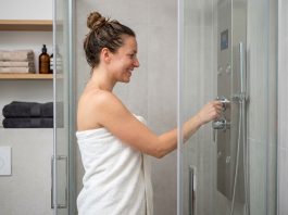 La colonne de douche hydromassante : plus de confort dans votre salle de bain Femme souriante dans la douche hydromassage moderne