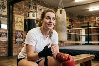 Une femme nouvellement arrivée à Paris enfile ses gants de boxe dans une salle conviviale au décor authentique