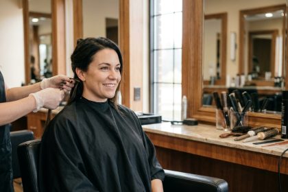 Femme en salon de coiffure recevant des extensions de cheveux naturels posées par une coiffeuse professionnelle