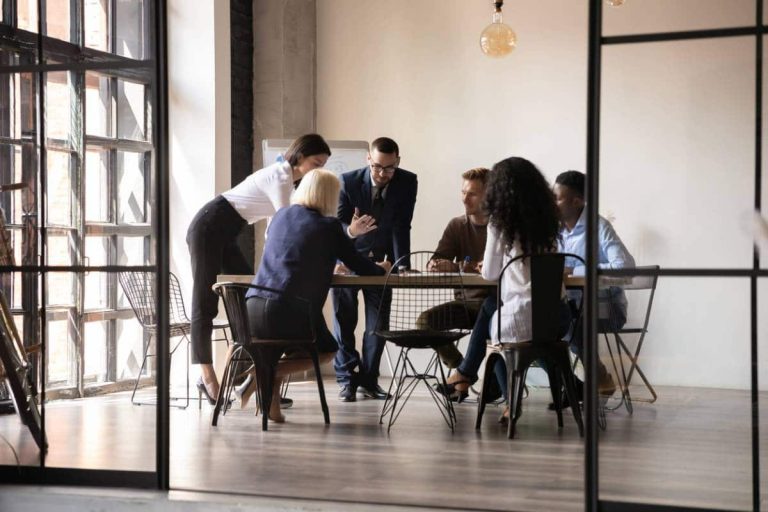 personnes discutant autour d'une table avec des documents et un ordinateur portable